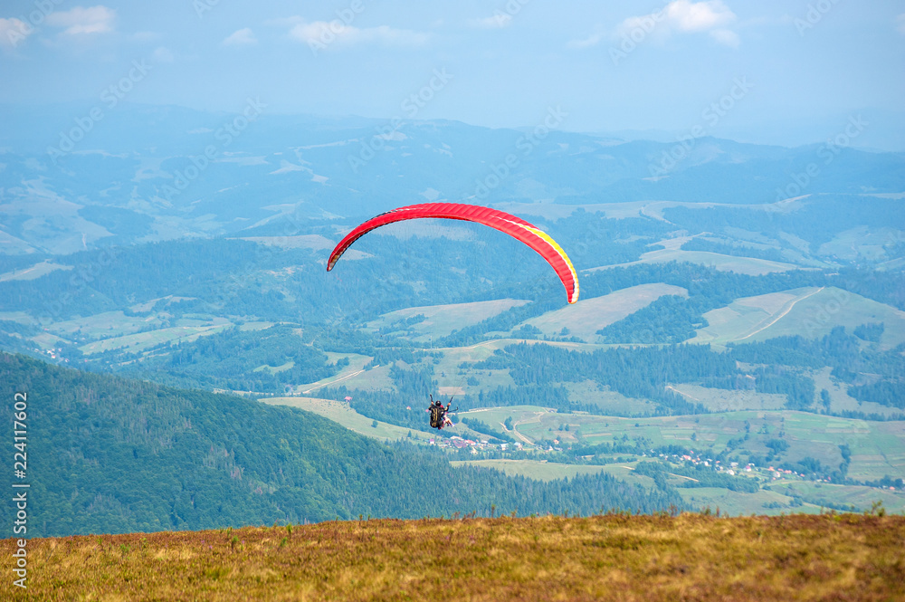 Paraglider takes off from the mountainside in the Carpathian Mountains. Paragliding in the mountains in the summer. Paraglider takes off from the mountainside in the Carpathian Mountains. Paragliding in the mountains in the summer.