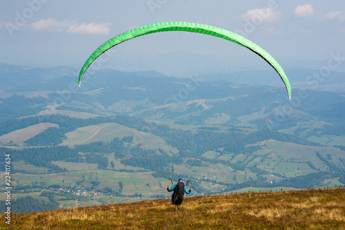 Paraglider takes off from the mountainside in the Carpathian Mountains. Paragliding in the mountains in the summer.