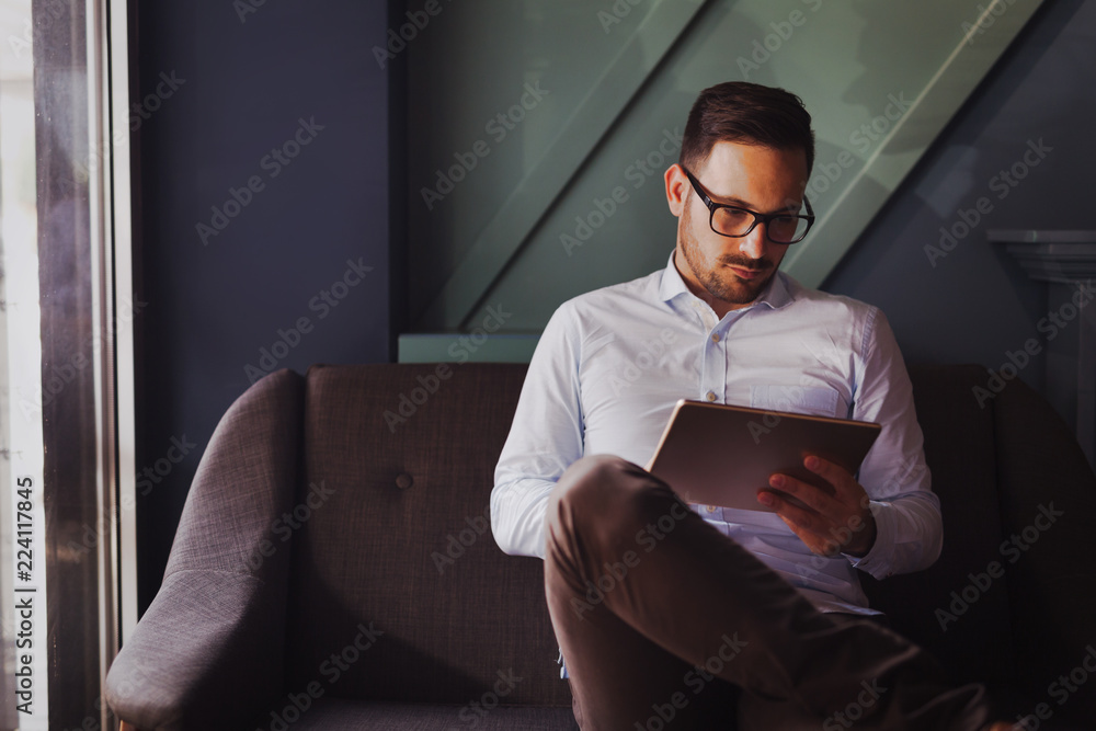 Portait of businessman in glasses holding tablet