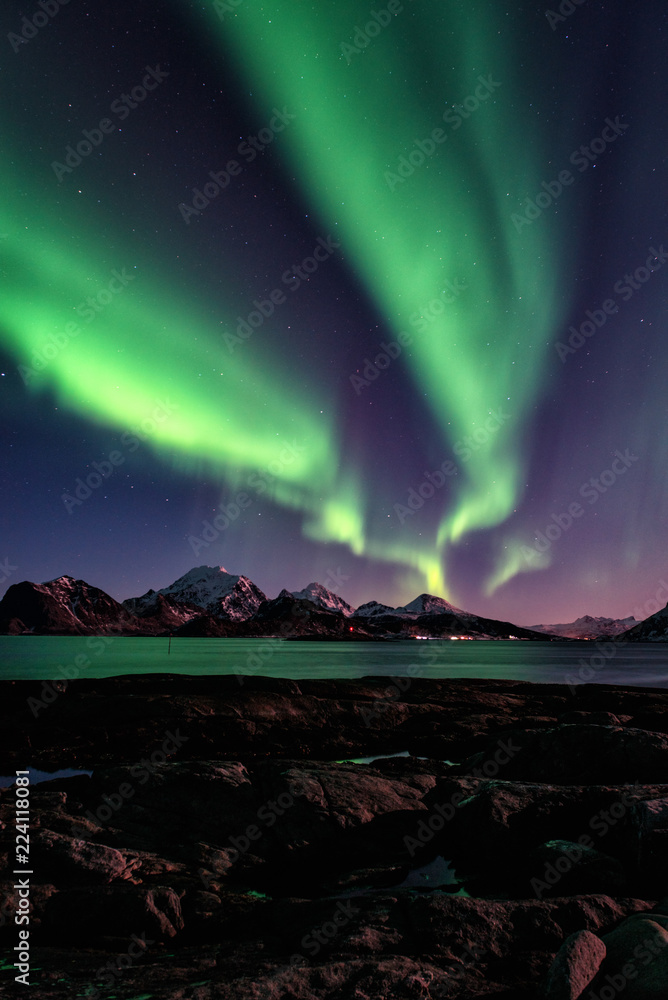 Night winter landscape with Northern lights, Aurora borealis. Scenery view of the Lofoten Islands, Norway. Vertical image