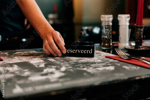 Obraz na plátně close up of a woman's hand setting a reserved sign on the restaurant table