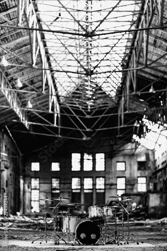 A white drum set stands in an abandoned hangar, an abandoned red brick plant. devastation, post apocalypse, urbex