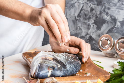 Process of cooking Dorado fish with lemon, olive oil and herbs. Female hands close-up. Concept of homemade food, culinary hobby