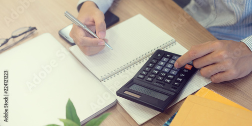 close up accountant business man writing cost estimate and pressing on calculator at office desk concept