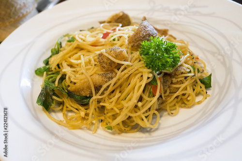 Close up of spicy spaghetti and dry fish in white plate.