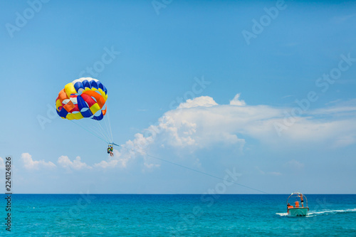 People flying on a colorful parachute towed by a motor boat