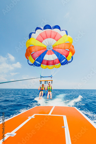Couple of tourists flying on a multi colored parachute