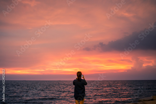 silhouette of young woman with open arms raised with sunset sky.