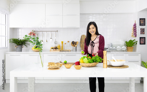 Beautiful Asian woman showing her new kitchen decoration and play with fake fruits and vegetables. Concept to modern housewife work.