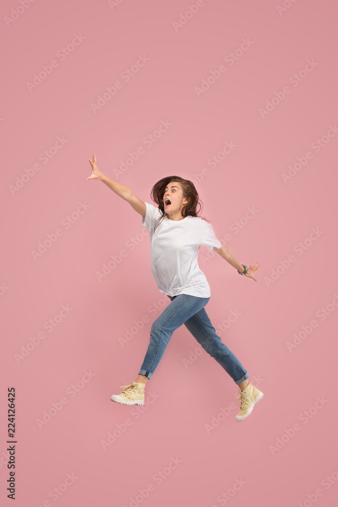 What is there interesting in the distance. seeking pretty happy young woman jumping and grabbing against pink studio background. Runnin girl in motion or movement. Human emotions and facial