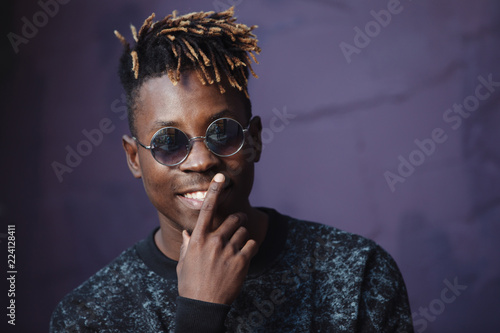 Stylish african american man rapper wear cool glasses at violet wall background