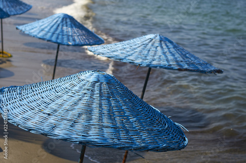 Fototapeta Naklejka Na Ścianę i Meble -  Beach with blue sun umbrellas and loungers. The coast resorts of the Aegean Sea of Turkey. Turgutreis , Bodrum.