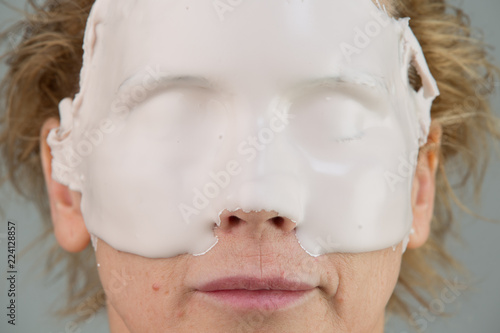 girl with facial mask looking at camera over white background. Cosmetic procedure. Beauty spa and cosmetology.