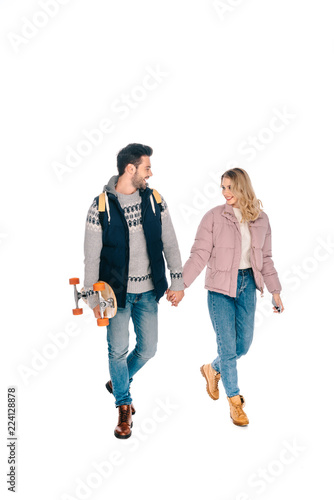 beautiful happy young couple holding hands and walking together, man holding skateboard isolated on white