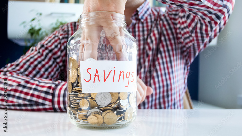 Φωτογραφία Closeup photo of young man emptying glass jar full of coins