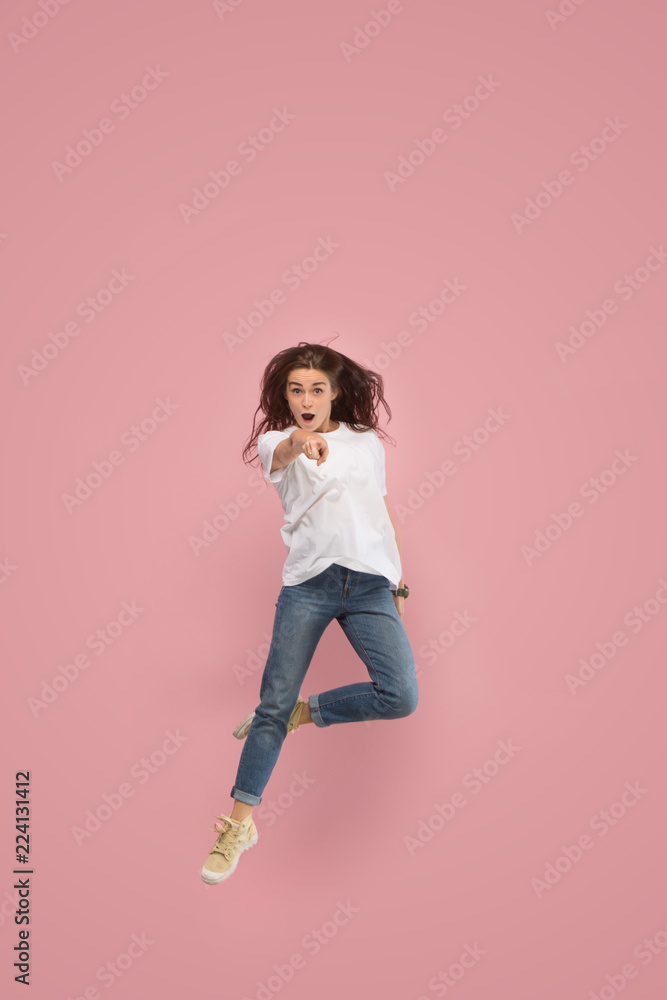 Freedom in moving. Mid-air shot of pretty happy young woman jumping and pointing to camera against pink studio background. Runnin girl in motion or movement. Human emotions and facial expressions Freedom in moving. Mid-air shot of pretty happy young woman jumping and pointing to camera against pink studio background. Runnin girl in motion or movement. Human emotions and facial expressions