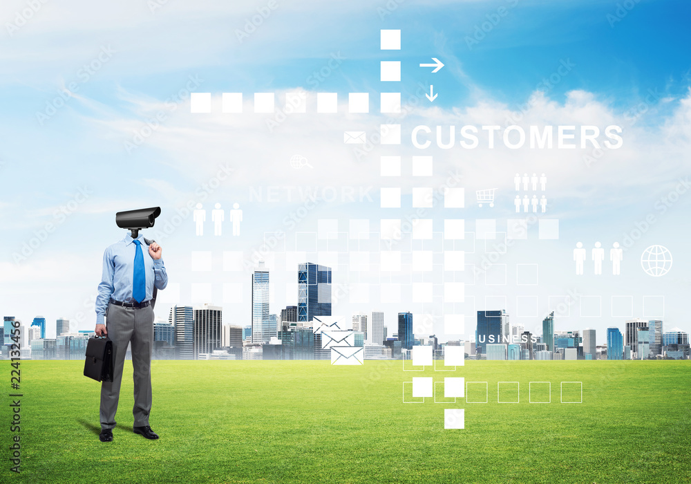 Camera headed man standing on green grass against modern cityscape Camera headed man standing on green grass against modern cityscape