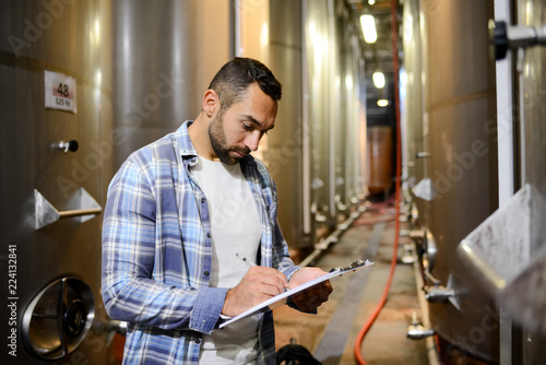 Konstfotografi handsome man winemaker in a winery wine cellar during harvest season with stainl