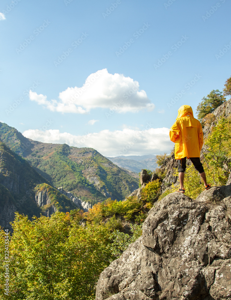 Obraz premium A man is standing on a rock and looking at the mountains