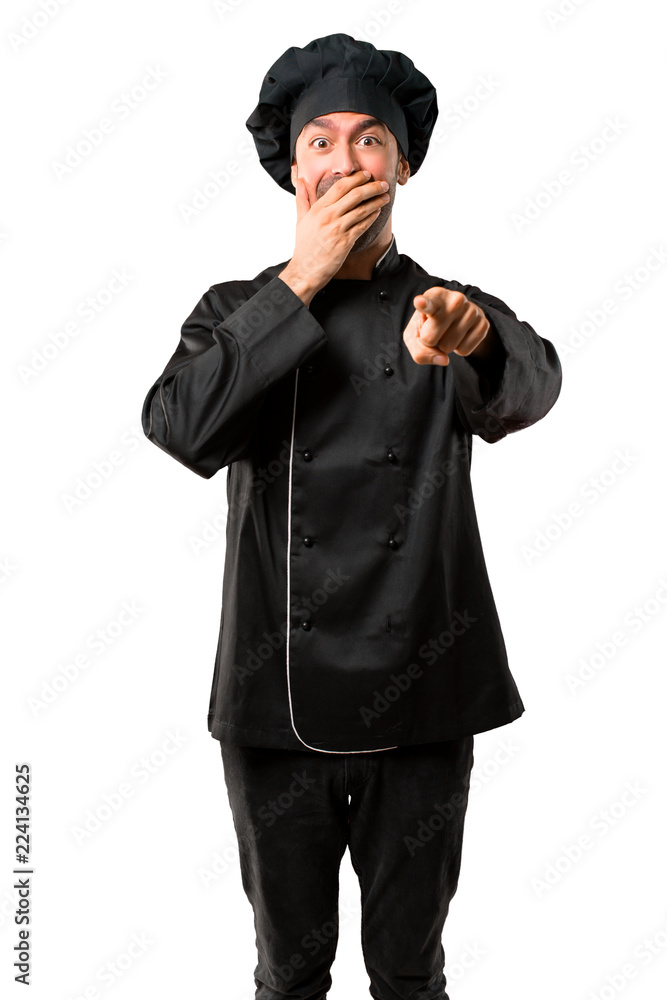 Chef man In black uniform pointing with finger at someone and laughing a lot while covering mouth on isolated white background Chef man In black uniform pointing with finger at someone and laughing a lot while covering mouth on isolated white background