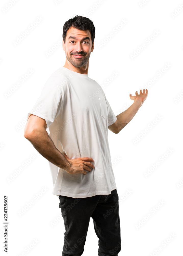 Young man with white shirt pointing back with the index finger presenting a product on isolated white background Young man with white shirt pointing back with the index finger presenting a product on isolated white background