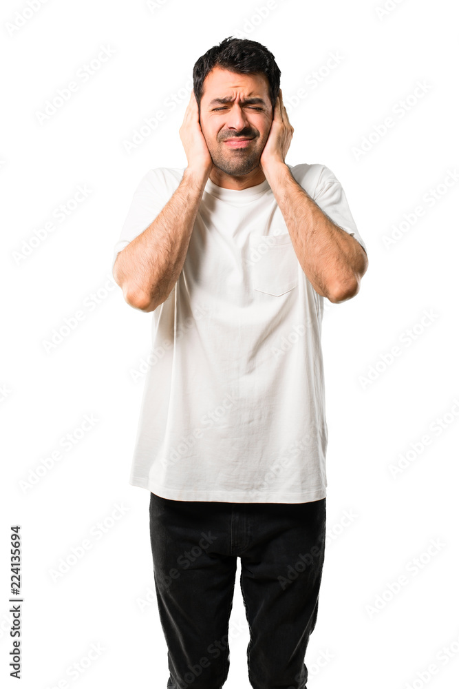 Fototapeta premium Young man with white shirt covering both ears with hands. Frustrated expression on isolated white background
