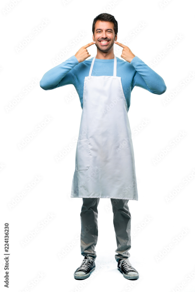 A full-length shot of a Man wearing an apron smiling with a happy and pleasant expression while pointing mouth and face with fingers on isolated background A full-length shot of a Man wearing an apron smiling with a happy and pleasant expression while pointing mouth and face with fingers on isolated background