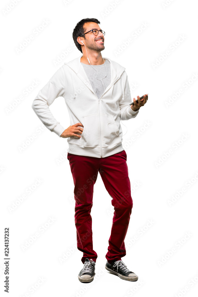 A full-length shot of a Man with glasses and listening music posing with arms at hip and laughing on white background A full-length shot of a Man with glasses and listening music posing with arms at hip and laughing on white background