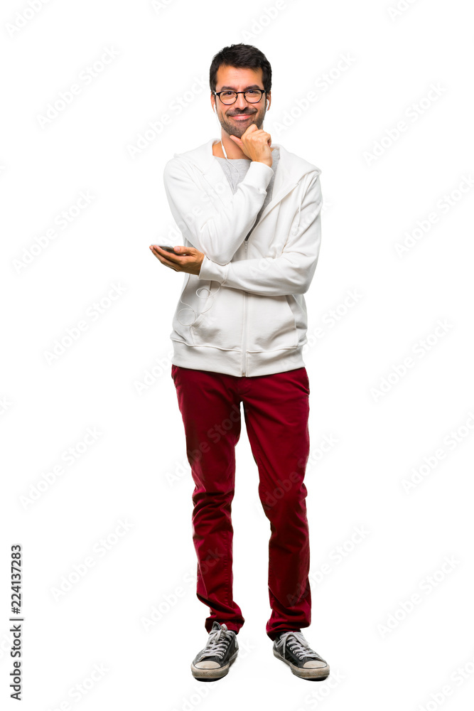A full-length shot of a Man with glasses and listening music smiling and looking to the front with confident face on white background A full-length shot of a Man with glasses and listening music smiling and looking to the front with confident face on white background