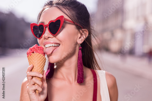 Amazing taste. Nice happy woman smiling while trying the cherry ice cream