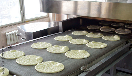 Conveyor with dough, billets for pizza.