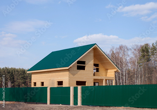 The wooden house behind a green fence in rural areas