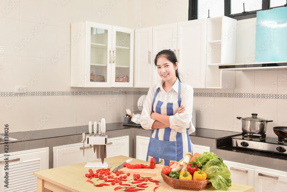 Asian housekeeper smiles in modern kitchen Asian housekeeper smiles in modern kitchen