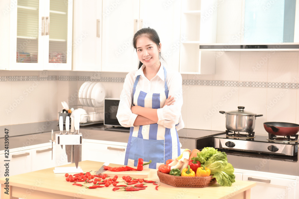 Asian housekeeper smiles in modern kitchen