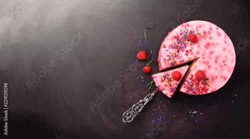 Delicious raspberry cake with fresh berries, rosemary and dry flowers on dark vintage background. Copy space for your text. Vegetarian, vegan food concept