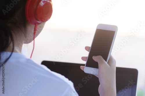 asian girl wearing red headphones working with  smartphone and laptop