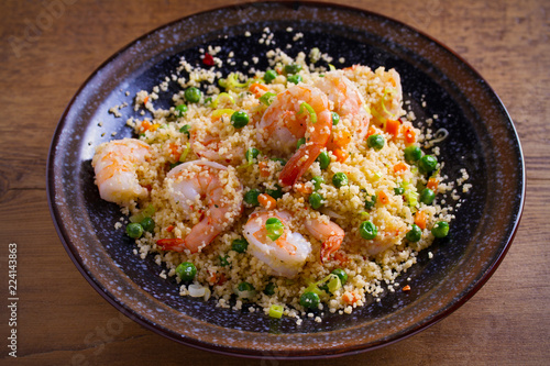 Shrimps with couscous, green peas, leeks and carrot. horizontal