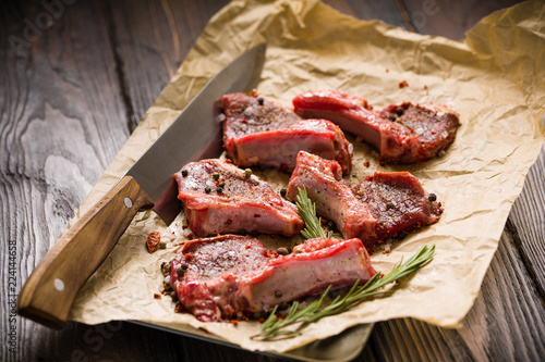 Raw lamb chops on a paper prepared for cooking on a rustic wooden table