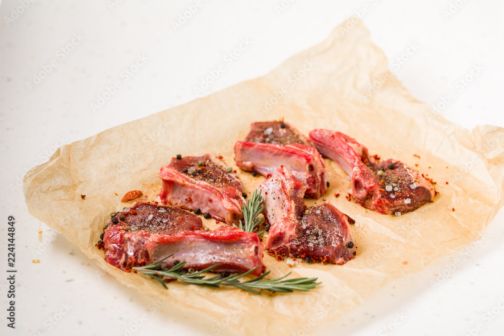 Raw lamb chops on a paper prepared for cooking on a marble table