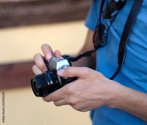 Close up, unrecognizable tourist man is holding an retro camera. Selective focus.