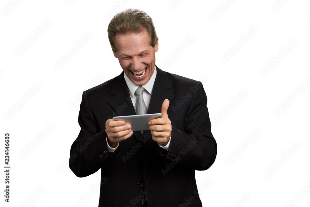 Cheerful funny manager playing on smartphone. Funny mature businessman playing online game on his phone, isolated on white background. Businessman having fun. Cheerful funny manager playing on smartphone. Funny mature businessman playing online game on his phone, isolated on white background. Businessman having fun.