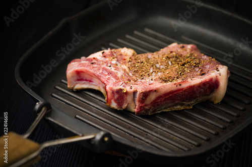 Close-up of Pork Steak Cooking On a Grill Pan With Herbs And Rock Salt. photo
