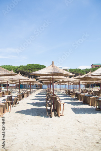 Albania. Golem. Beach shoreline with sun umbrellas made from straw. A blue sky on the Adriatic Sea.