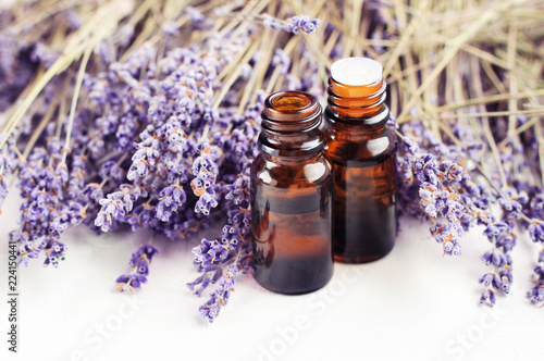 Dropper bottle of lavandula essential oil, bunch of dried purple lavender blossom white table. Herbal aromatherapy & SKincare. 