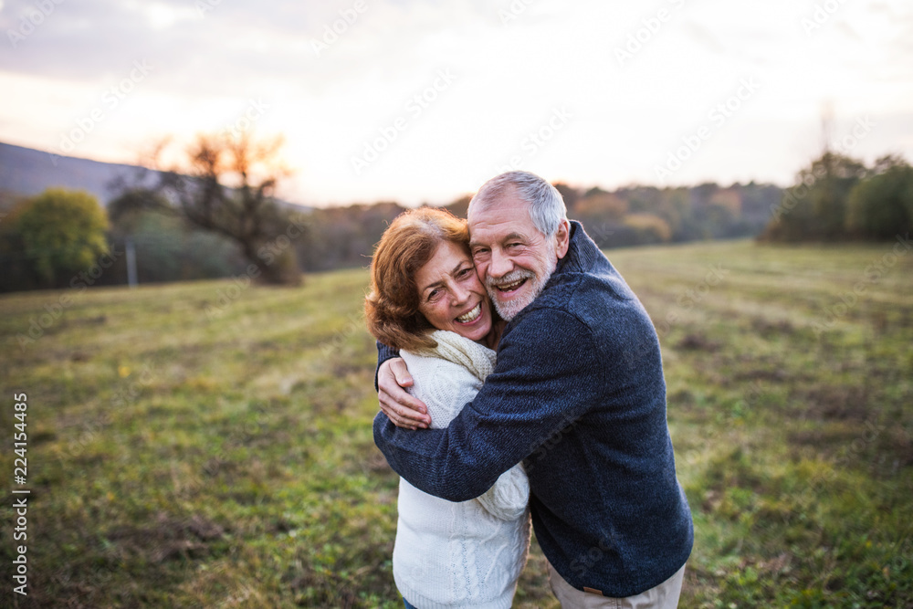 Senior couple hugging in an autumn nature at sunset.