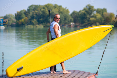 Sporty man stands on the beach with a SUP board