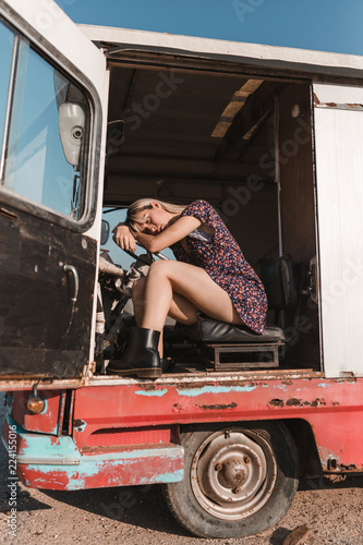Young woman leaning her head on steering wheel in old van