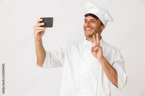 Chef man isolated over white wall background take a selfie by mobile phone.