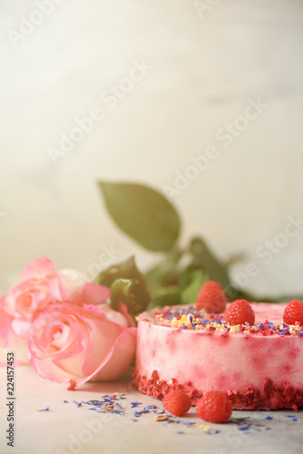 Pink roses and raspberry cake with fresh berries, rosemary, dry flowers on concrete background. Copy space for your text. Birthday party concept
