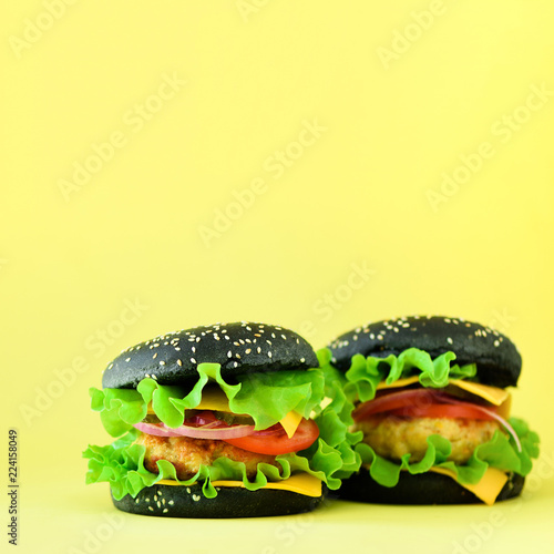 Fast food concept. Square crop. Juicy hamburger on yellow background. Take away meal. Unhealthy diet frame with copy space